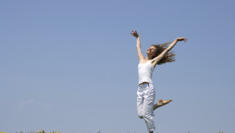 Smiling girl dancing in dandelion field